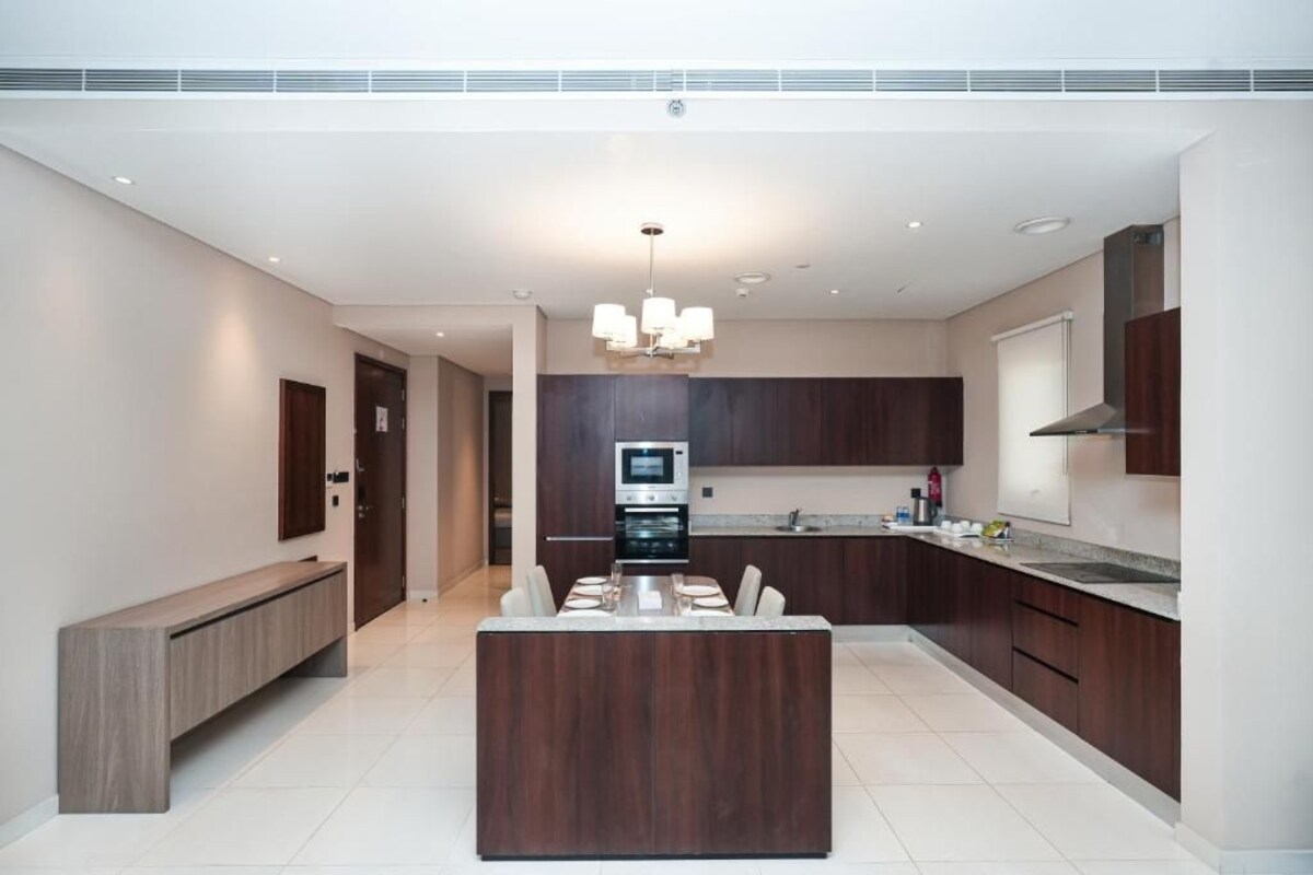 A modern kitchen with dark wood cabinets, a central island, and a built-in oven.