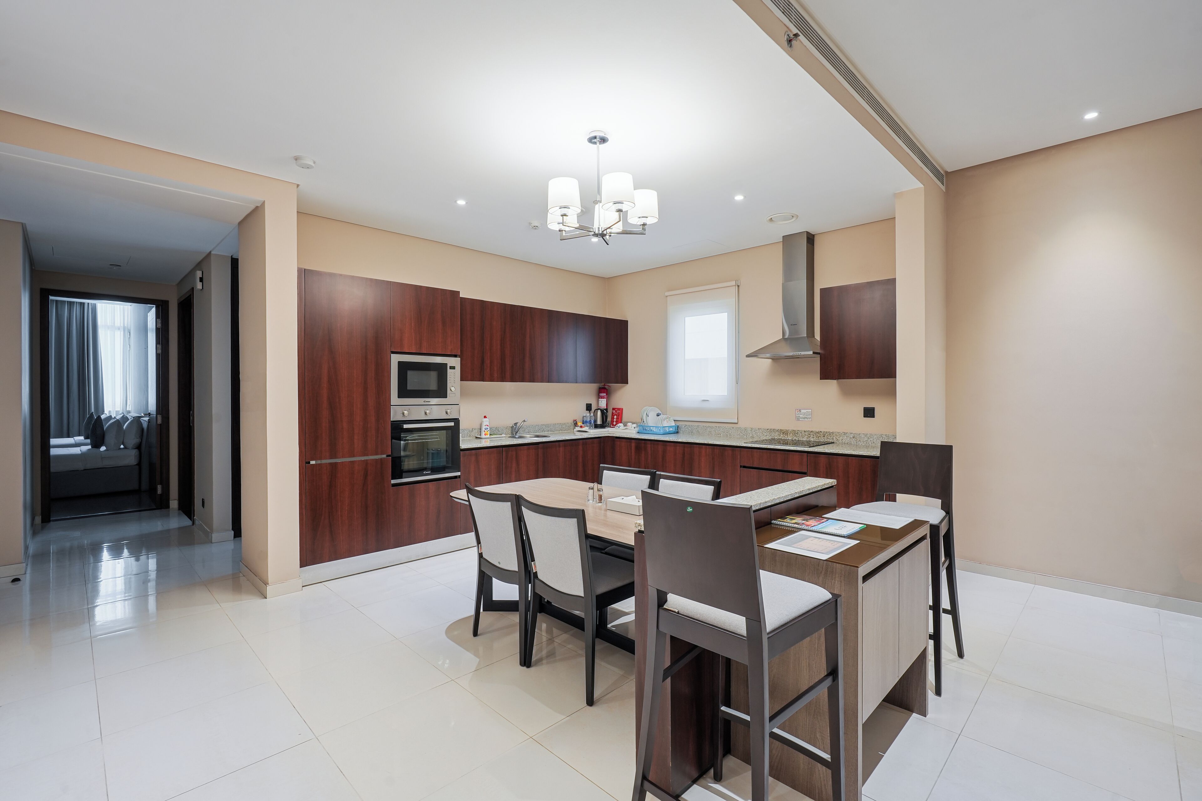 A modern kitchen with dark wood cabinets, a central island, and a dining area with chairs.