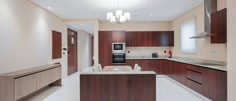 Una cocina moderna con armarios de madera, una isla central y electrodomésticos integrados.