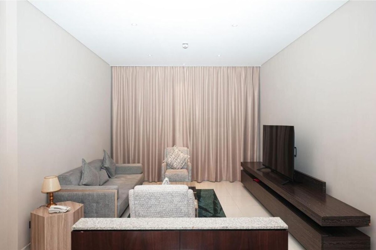 A modern living room with a sofa, armchair, TV, and a small side table.