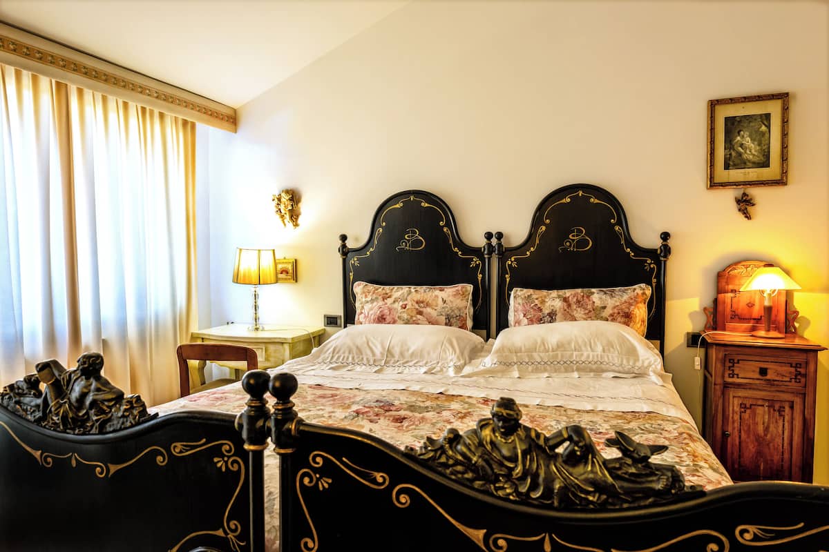 A bedroom with a double bed, two nightstands, a chair, and a lamp.