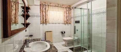 A bathroom with a sink, toilet, and glass shower enclosure.