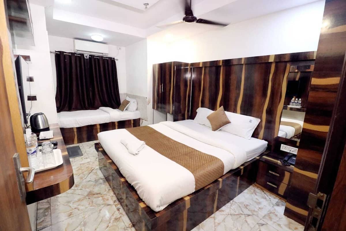 A hotel room with a bed, a bedside table, a mirror, a window with curtains, and a ceiling fan.
