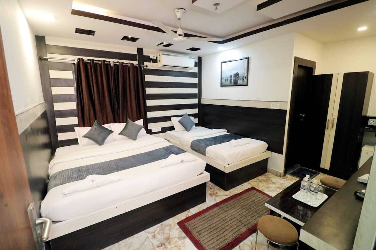 A hotel room with two beds, a desk, a chair, a small table, and a bathroom door.