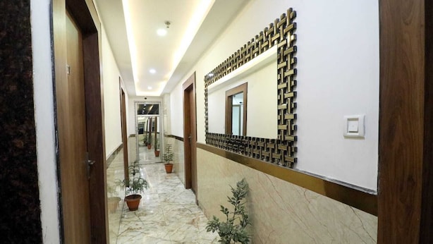 A hotel hallway with marble flooring, potted plants, and a decorative wall panel. - hotel best buy (Kolkata)