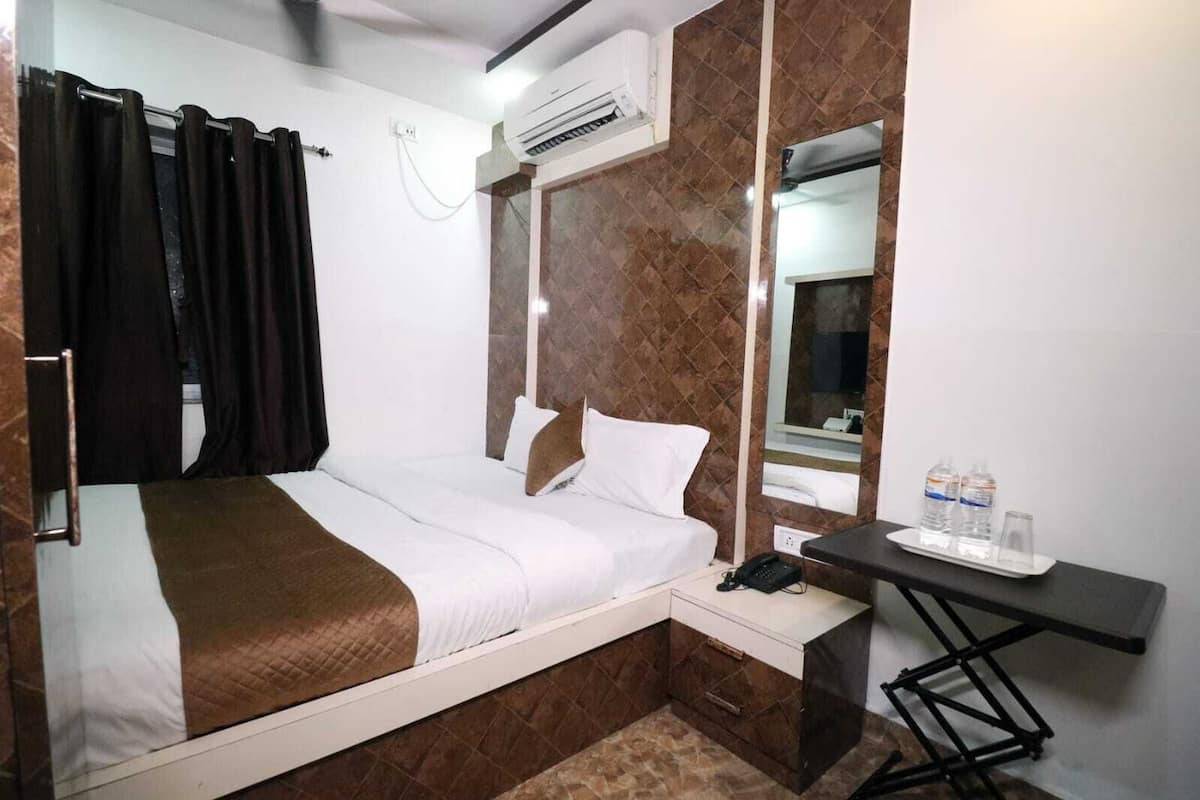 A hotel room with a bed, a desk, a phone, and a mirror.