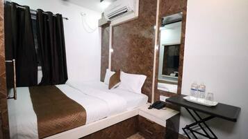 A hotel room with a bed, a desk, a phone, and a mirror.