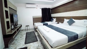 A hotel room with a large bed, a smaller bed, a TV, a ceiling fan, and a marble floor. - hotel best buy (Kolkata)