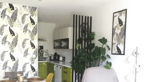 A modern kitchen with green cabinets, a dining area with a yellow chair, and a white armchair. - Apartment 44 m2. Type 2 (Aix-en-Provence)