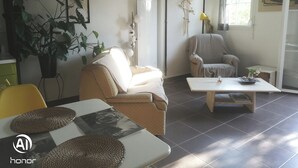 A living room with a sofa, armchair, coffee table, and a dining table with placemats. - Apartment 44 m2. Type 2 (Aix-en-Provence)