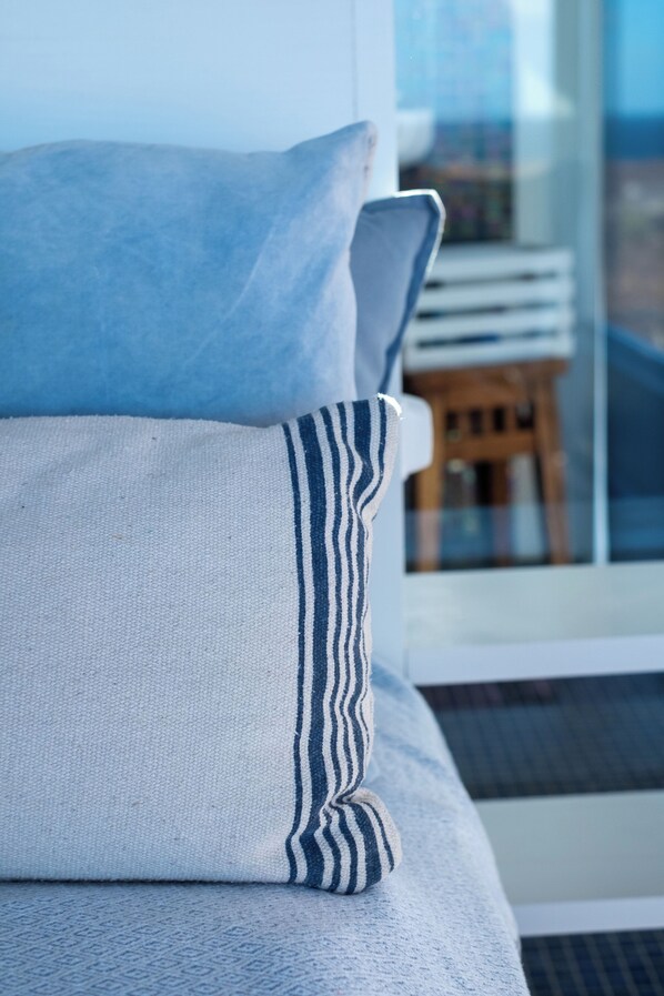 A bed with a grey and white striped pillow, a grey pillow, and a white pillow. - Villa by the Sea (Haria)