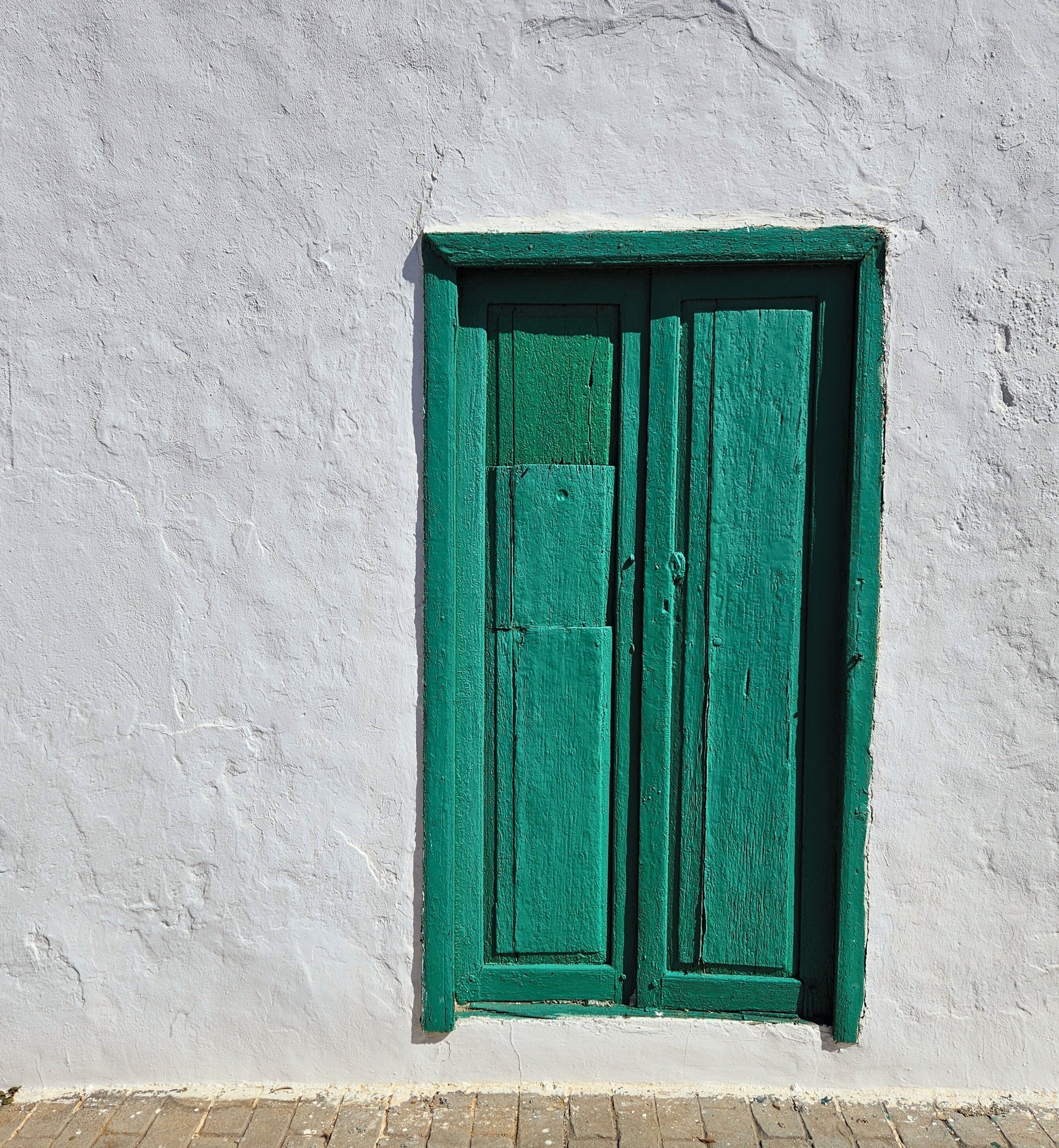 A white wall with a green door.