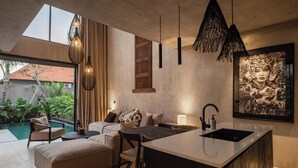 Una cocina moderna con una isla central, iluminación colgante y una obra de arte grande enmarcada en la pared.
