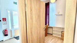 Een houten deur die leidt naar een ruimte met een lamp, een brandblusser en een witte plank.