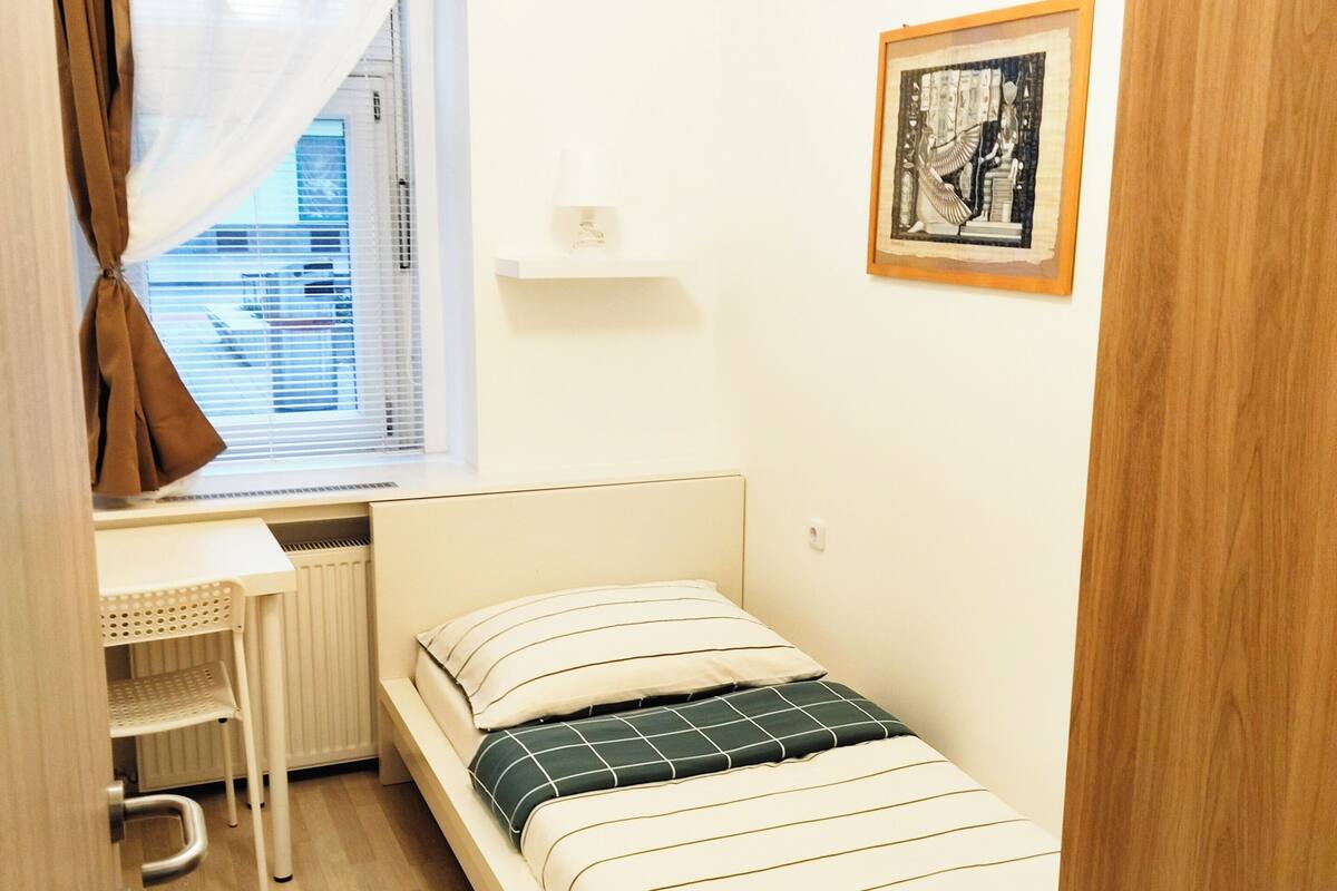 Un dormitorio pequeño y ordenado con una cama individual, un escritorio y un radiador.
