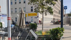 Een openbaar plein met een standbeeld, zitplaatsen buiten en een gebouw met een bordje 'Ludwig'.
