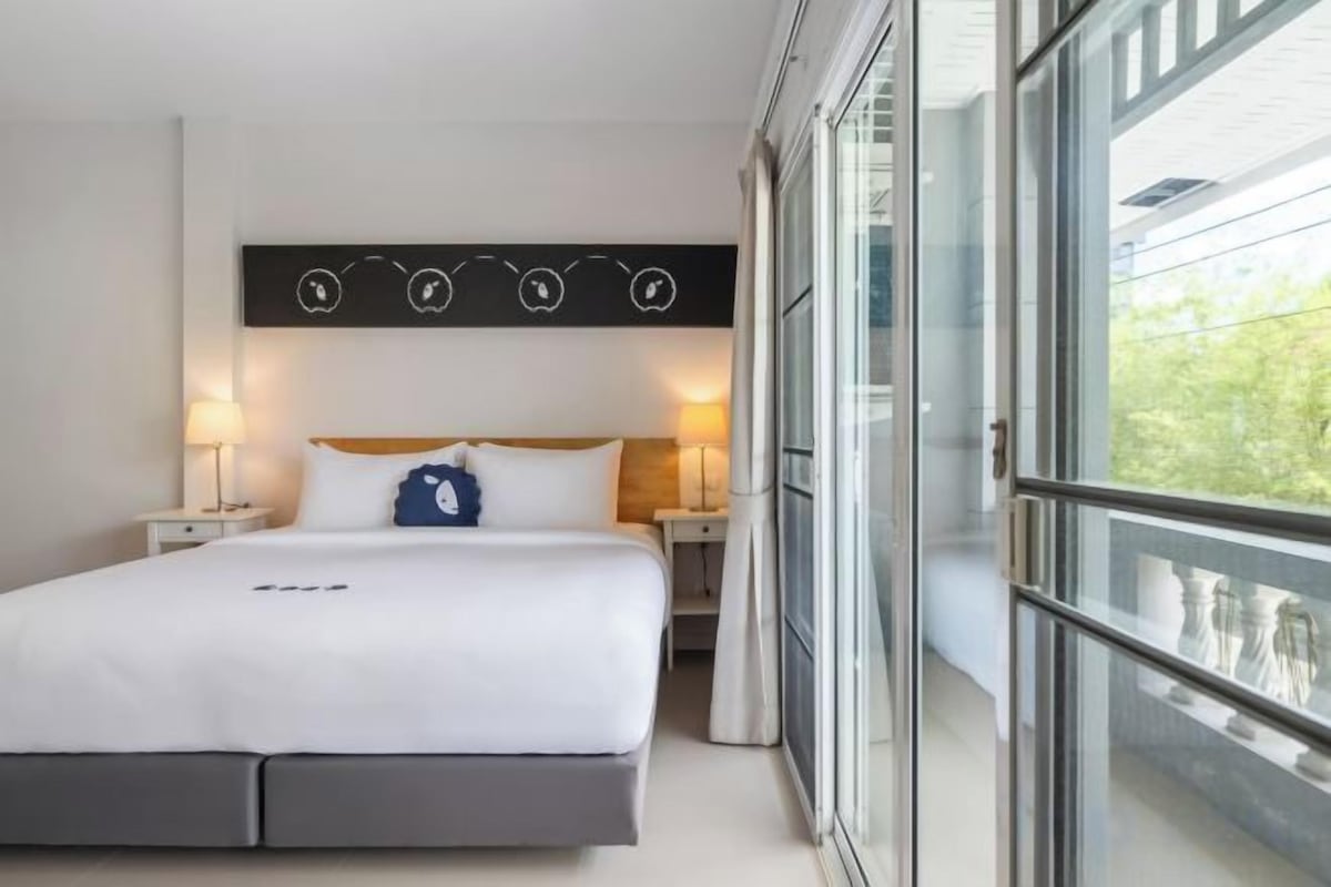 Una habitación de hotel con una cama grande, mesitas de noche, un ventanal y vistas al exterior.