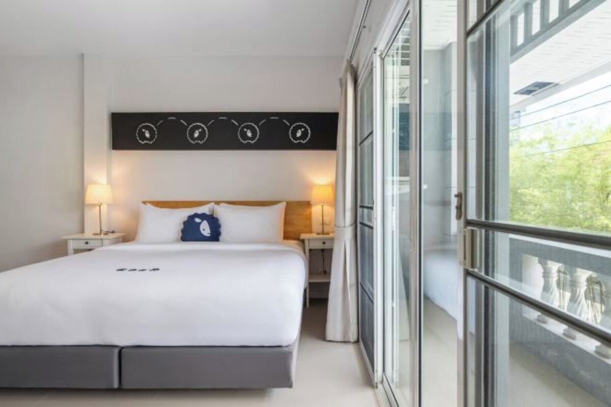 Une chambre d’hôtel moderne avec un grand lit, des lampes de chevet, un élément décoratif mural et un balcon avec vue.