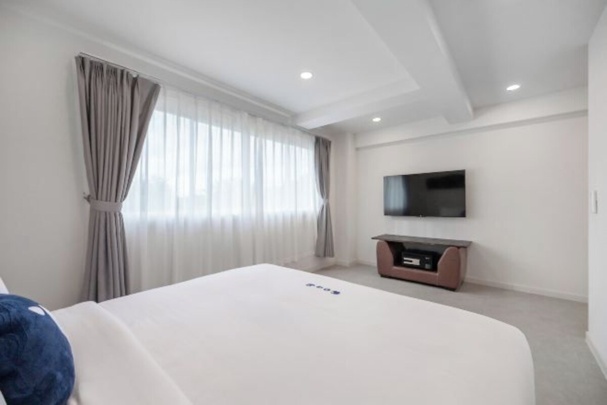Une chambre d’hôtel avec un grand lit, un téléviseur à écran plat fixé au mur et un petit meuble pour les équipements de divertissement.