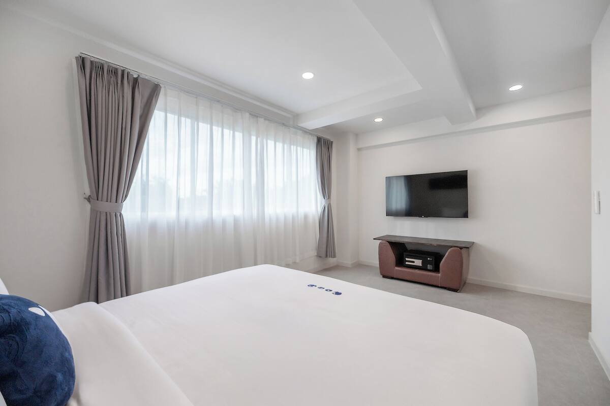 Een moderne hotelkamer met een groot bed, een flatscreen televisie aan de muur en een klein tv-meubel.