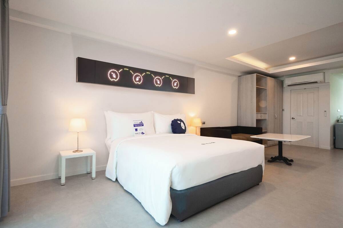 Een moderne hotelkamer met een groot bed, nachtkastjes met lampen, een bureau en een kledingkast.