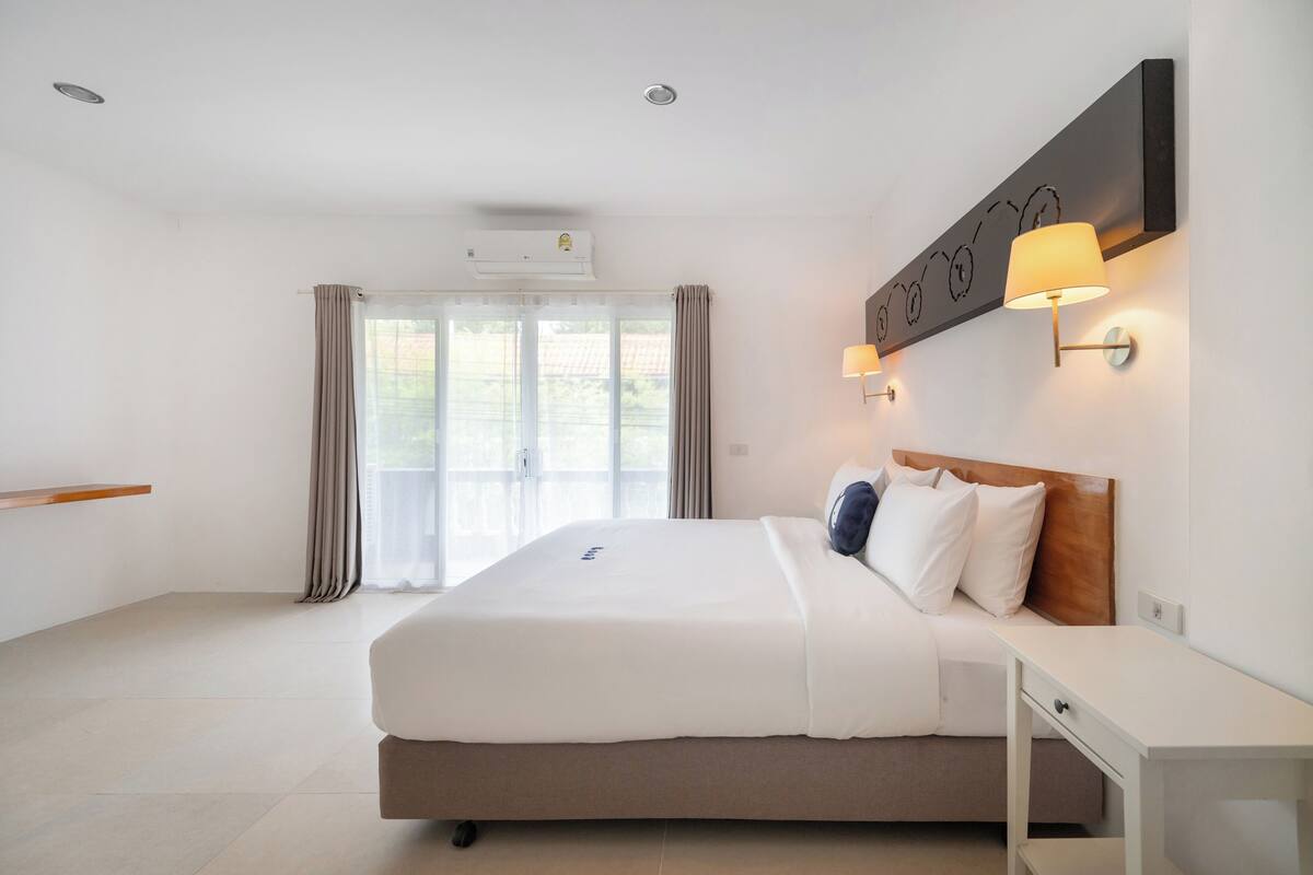 Een moderne hotelkamer met een groot bed, nachtkastje en een wandlamp.