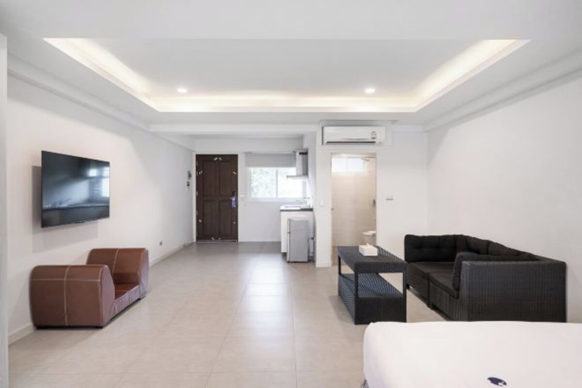 Une chambre d’hôtel moderne équipée d’un téléviseur à écran plat, d’un canapé, d’une table à manger et d’une kitchenette.