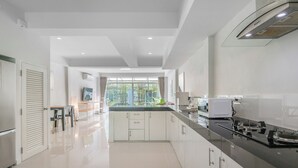 Una cocina moderna con armarios blancos, encimera negra y campana extractora de acero inoxidable.