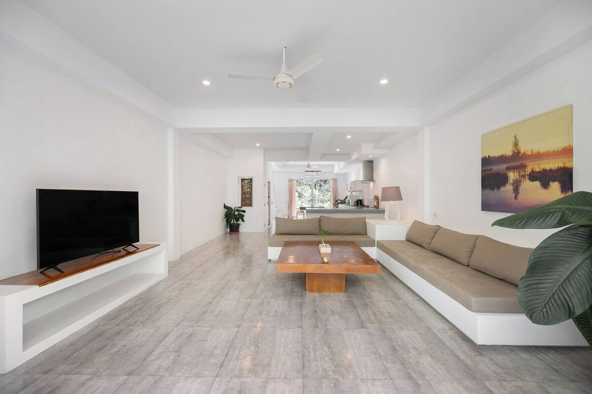 Een moderne woonkamer met een flatscreen televisie, een houten salontafel en een beige bank.
