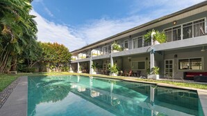Un hotel moderno con piscina, zona de estar al aire libre y abundante vegetación.