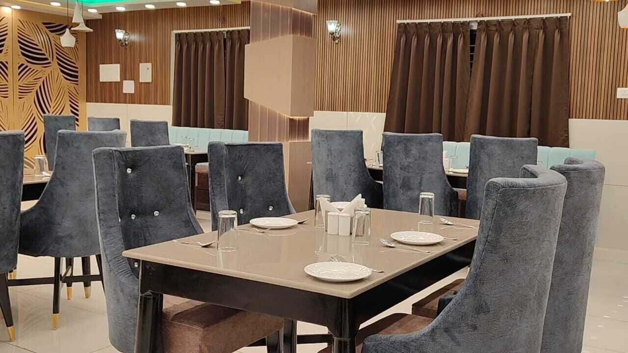 Een eetruimte met meerdere tafels en stoelen, elk voorzien van borden, glazen en bestek.