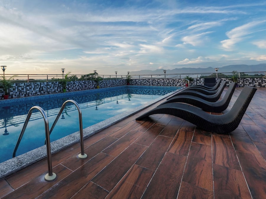 Una piscina amb un vorejador de rajola, una terrassa de fusta i gandules.