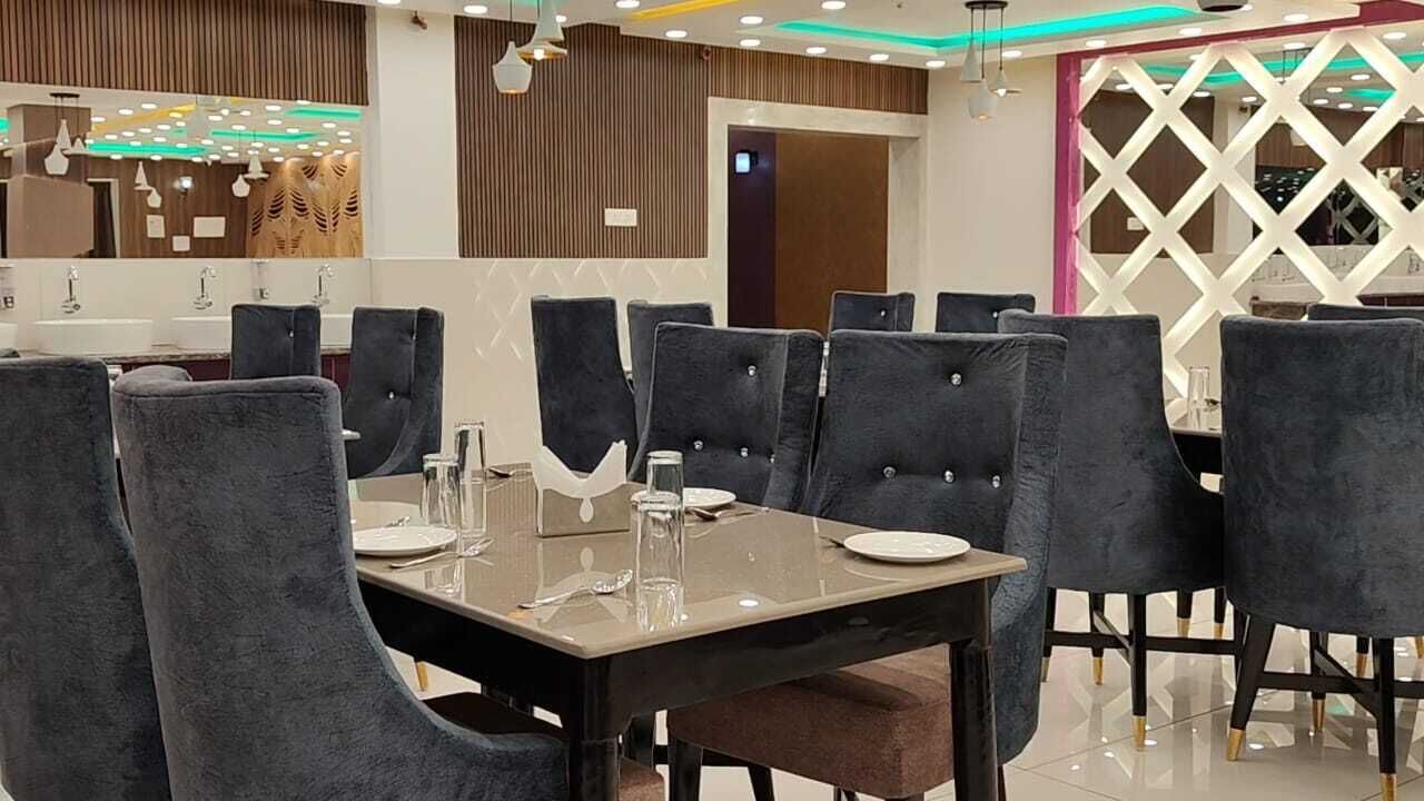 A restaurant with a modern interior, featuring a central dining table with chairs, a counter with a mirror, and a decorative wall with a geometric pattern.