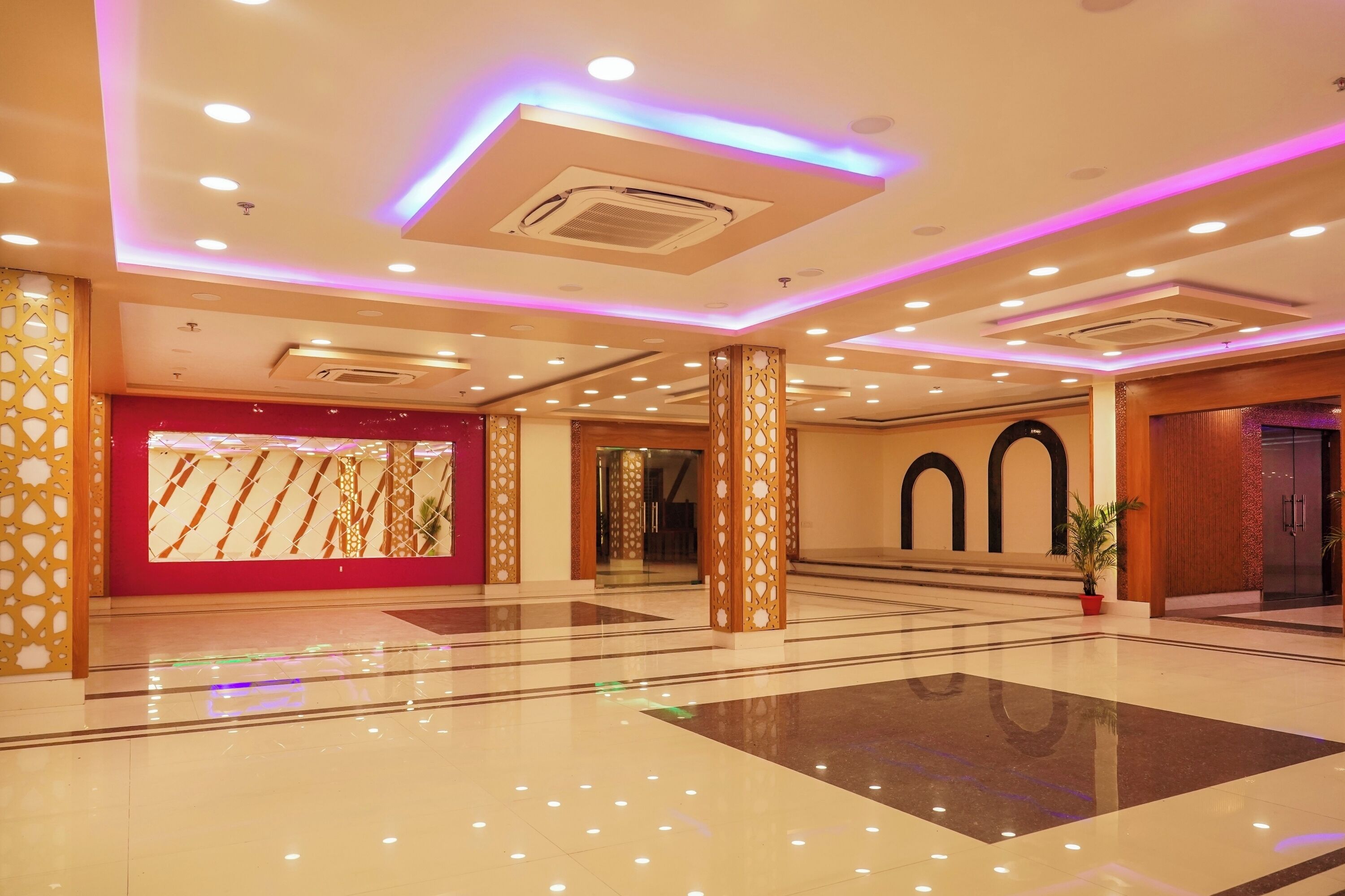 A spacious lobby with a polished floor, decorative pillars, and a red accent wall.