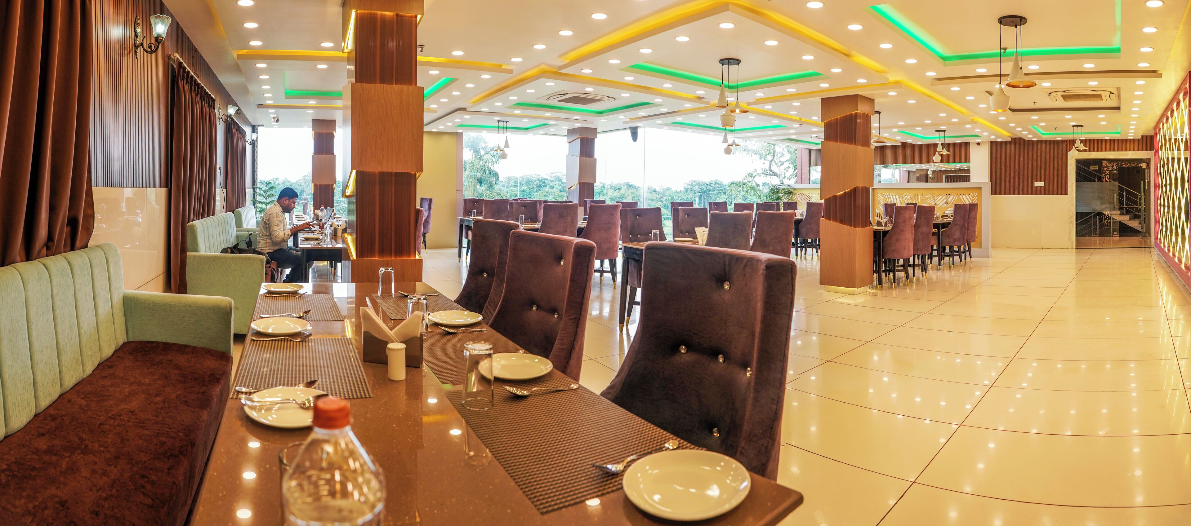 A restaurant with a long dining table set for a meal, surrounded by high-backed chairs.