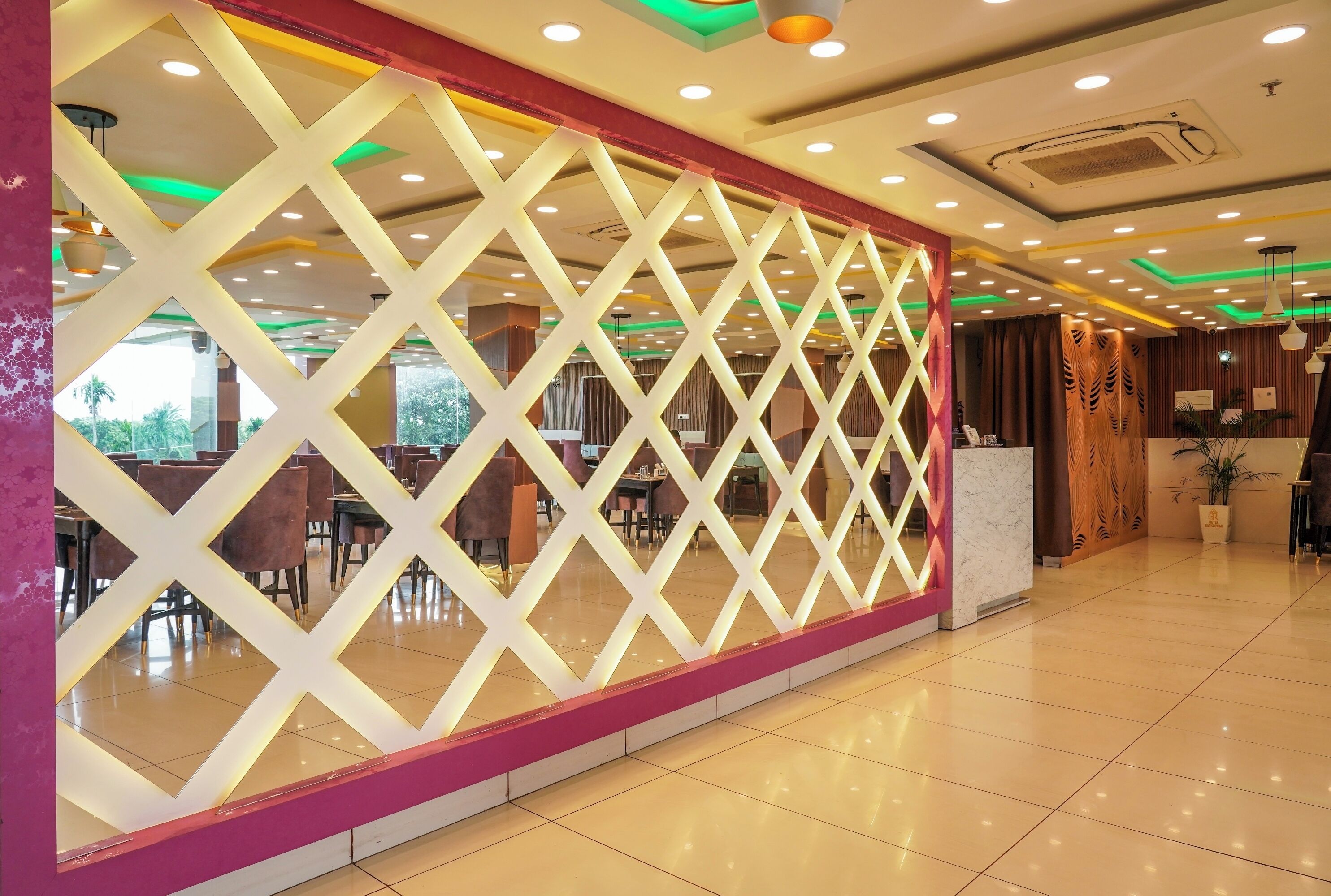 A modern hotel lobby with a geometric decorative wall, a reception desk, and a clean, tiled floor.