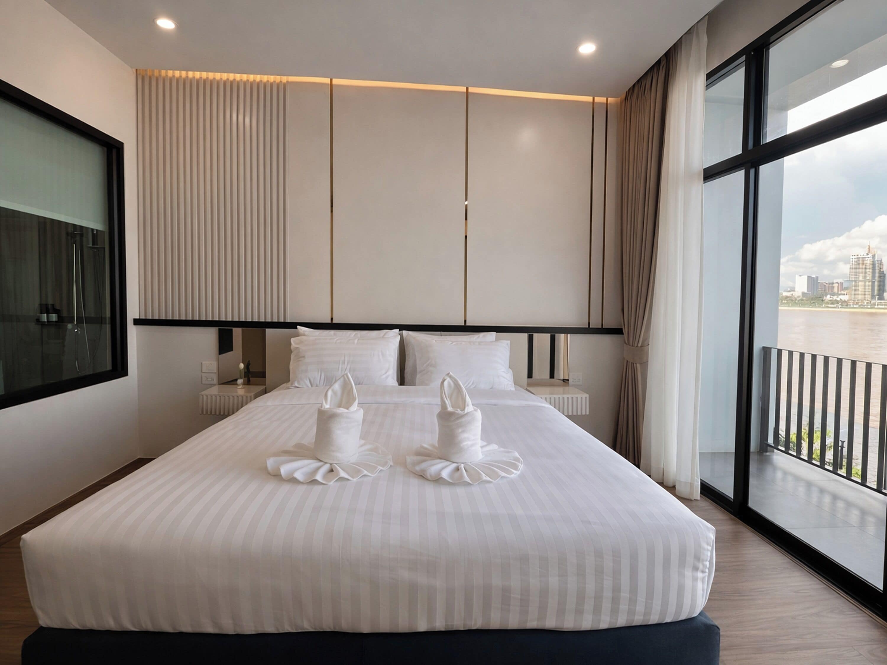 A modern hotel room with a large bed, a view of the city, and a balcony.