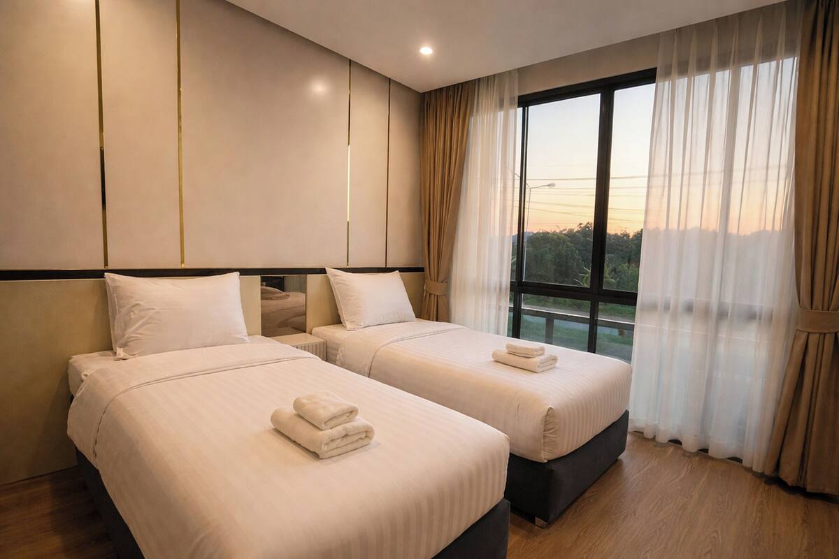 A hotel room with two beds, a large window with curtains, and a view of the outdoors.