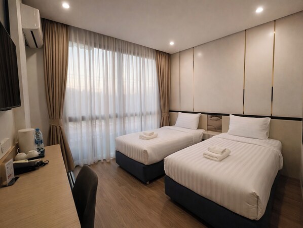 A hotel room with two beds, a desk, a chair, a TV, and a window with curtains. - View khong Hotel (Chiang Saen)