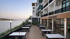 A waterfront restaurant with outdoor seating, a view of the water, and a building with a 'VIEW CAFE' sign. - View khong Hotel (Chiang Saen)