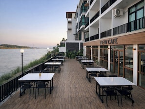 A waterfront restaurant with outdoor seating, a view of the water, and a building with a 'VIEW CAFE' sign. - View khong Hotel (Chiang Saen)