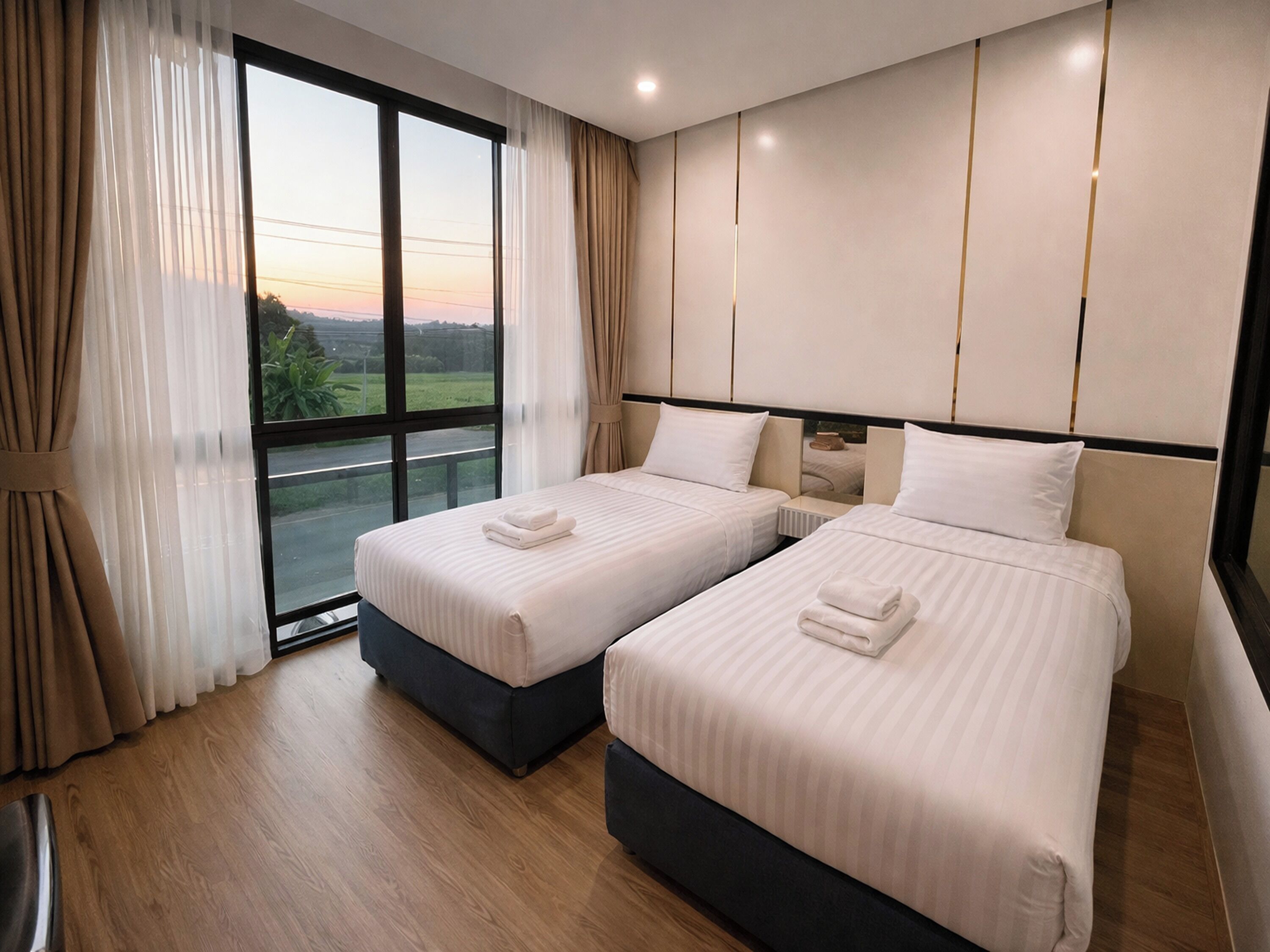 Una habitación de hotel con dos camas, un ventanal grande y vistas al exterior.