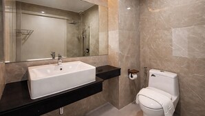 A modern bathroom with a large mirror, a white sink, a toilet, and a shower area. - View khong Hotel (Chiang Saen)