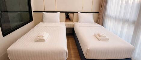 A hotel room with two beds, a large window, and a curtain.