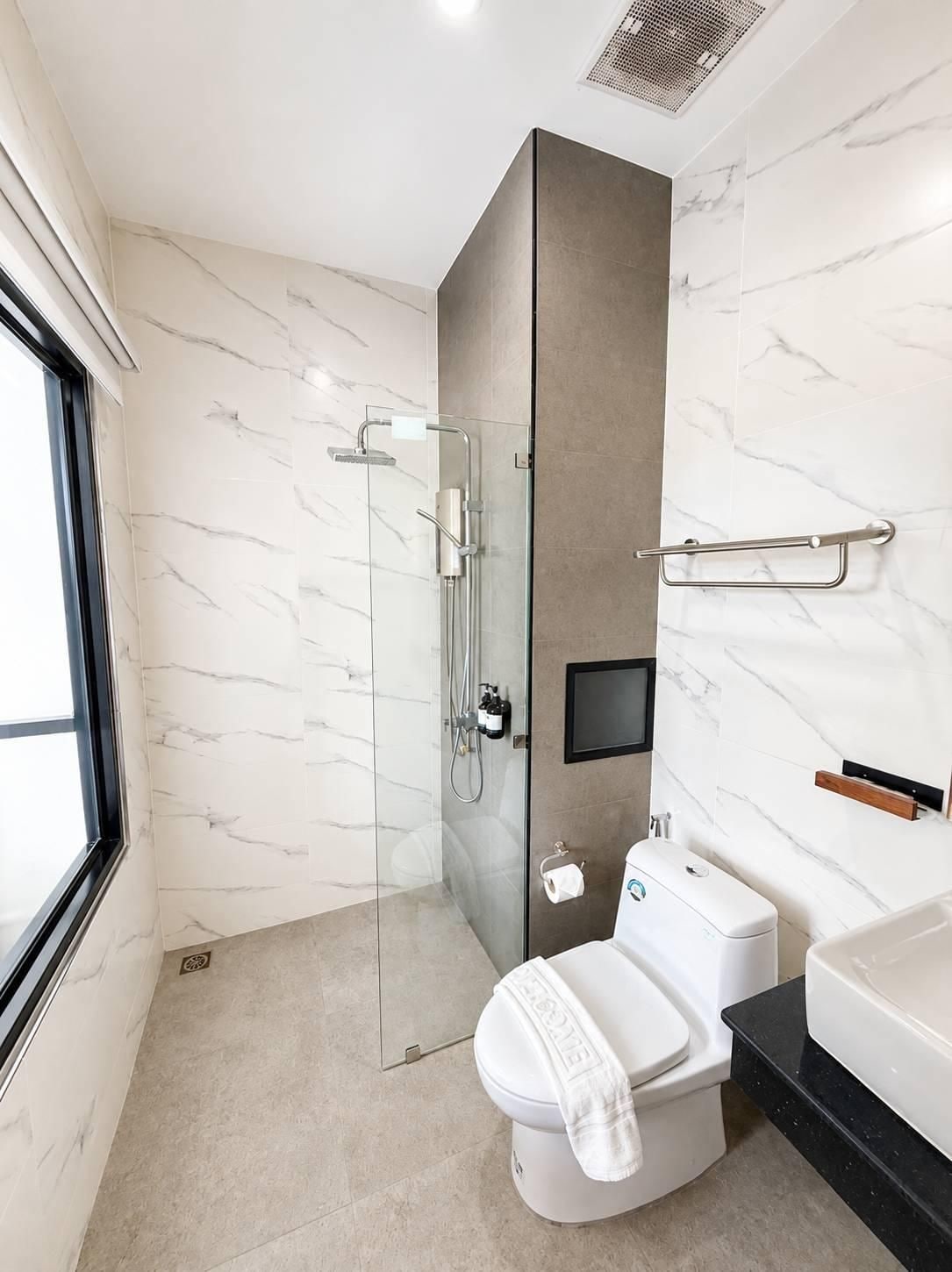 A modern bathroom with a glass-enclosed shower, a toilet, and a sink.