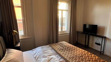 Ein Hotelzimmer mit Bett, Fernseher auf einem Schrank und einem Fenster mit Vorhängen.