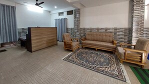 Un salon spacieux comprenant un ensemble de canapés, une table basse en bois et un tapis à motifs.