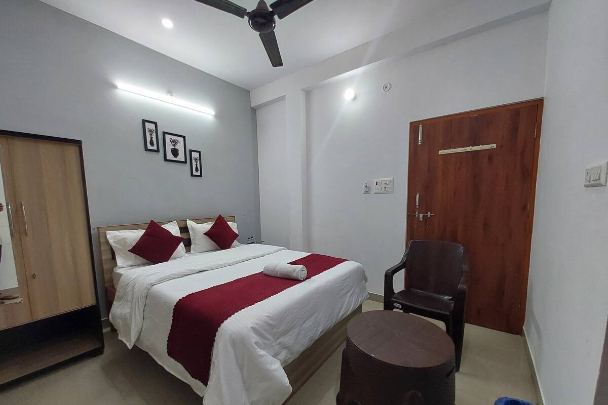Ein Hotelzimmer mit Bett, Holzschrank, Stuhl und einem kleinen Hocker.