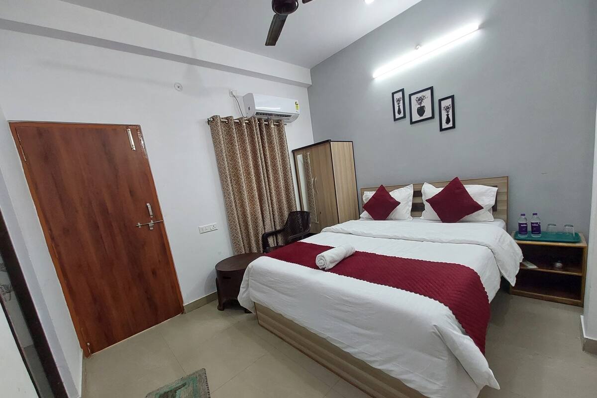 Ein Hotelzimmer mit Bett, Kleiderschrank, Spiegel, Schreibtisch und Wasserspender.