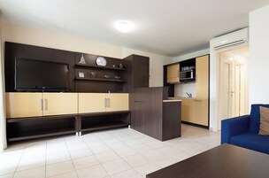 Una cocina moderna con electrodomésticos integrados, un televisor de pantalla plana y una zona de comedor con un sofá azul.
